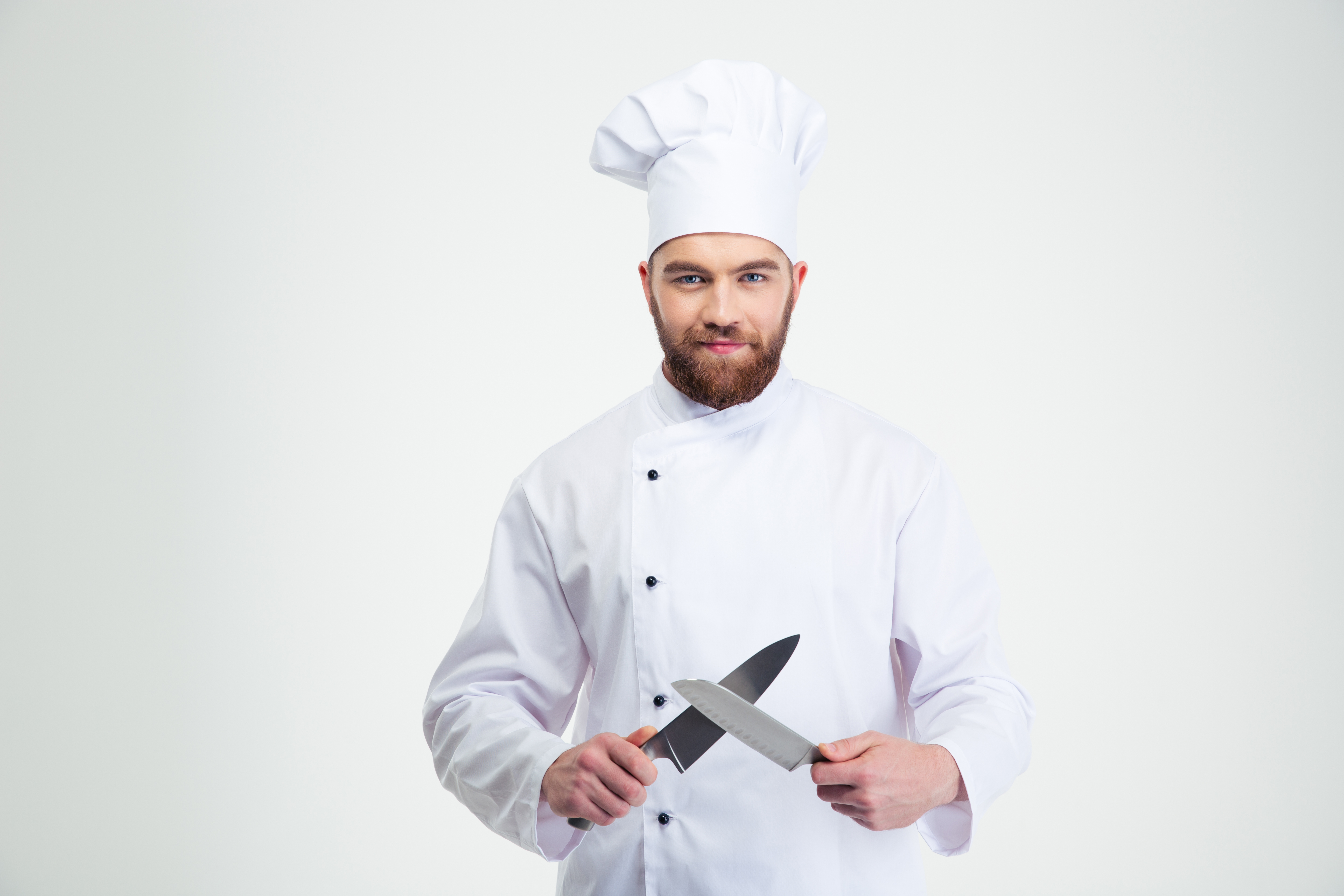 Portrait of a happy male chef cook sharpening knife isolated on a whit